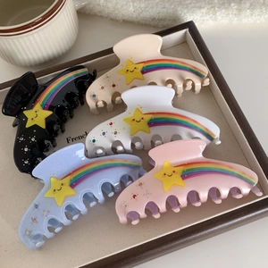 Five colorful rainbow star hair claws in black, beige, and pink colors on wooden tray