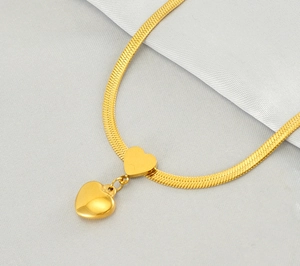 Detailed close-up of golden snake chain necklace with dual puffed heart pendants