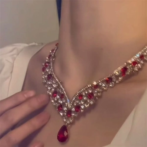 Close-up of elegant V-shaped necklace with red teardrop zircon gemstone on a model