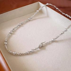 Detail of silver pearl necklace with textured metal beads and unique hook clasp