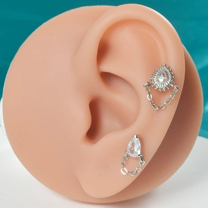 Détail de boucles d'oreilles papillon et goutte d'eau argentées avec chaînes et clous