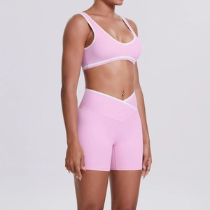 Detail of pink yoga set showing V-waist leggings and vest with white piping trim