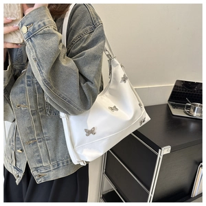 Détail des charms papillons argentés sur le sac porté épaule hobo blanc en cuir