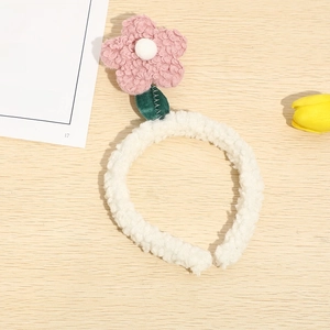 Detail of pink plush tulip headband with green leaves on a natural wood background