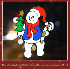 Detail of Christmas snowman window sticker with red hat and festive tree on glass