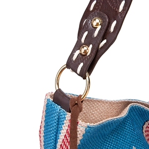 Detail of woven boho shoulder bag showing leather strap with contrast stitching and metal rings