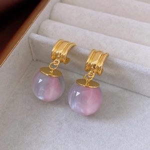 Macro view of gold striped geometric earrings with iridescent aurora resin ball charms