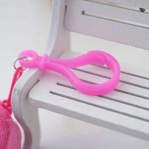 Dettaglio di un moschettone in plastica rosa brillante su una panca in legno bianca