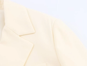 Close-up of cream-colored lapel and shoulder detail on a long tailored women blazer