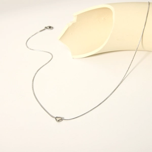Minimalist silver heart pendant necklace with sleek snake chain on a modern artistic backdrop