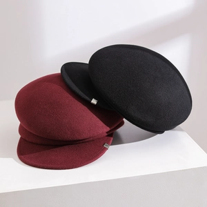 Close-up of premium wool felt newsboy hats in burgundy and black stacked on white