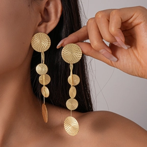 Detail shot of long gold tassel earrings with textured round plates on model
