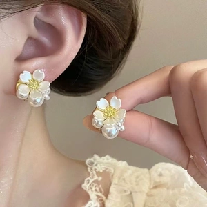 Detail of white flower stud earrings with gold stamen and elegant imitation pearls