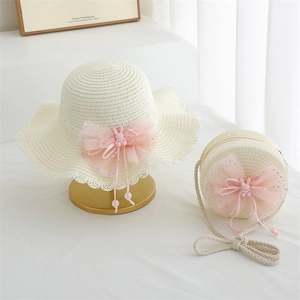 Detail of cream straw hat and matching round bag with pink bow and bunny charm