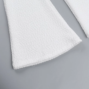 Detail shot of white textured fabric showing soft boucle material on wide leg pants hem