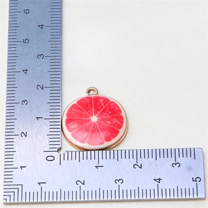 Macro shot of 2.5cm grapefruit slice charm with gold plating and red enamel details