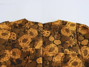 Detail van gouden jacquardstof met vintage bloemenpatronen en een onzichtbare rits achter
