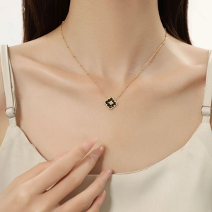 Close-up of gold stainless steel necklace featuring a black clover pendant with a center zircon