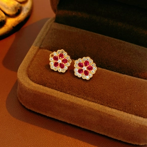 Macro shot of gold-tone flower earrings with sparkling red and clear zircon stones