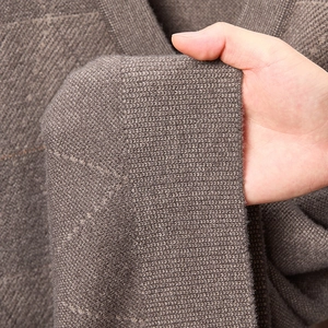 Detailaufnahme der braunen Strickpullover-Textur mit Rautenmuster und Gewebedichte