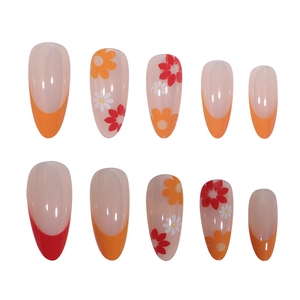 Macro shot of French almond press-on nails with red-orange borders and daisy floral patterns