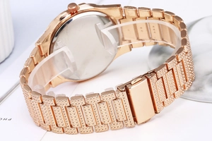 Macro shot of rose gold metal link strap and secure folding clasp on women's watch