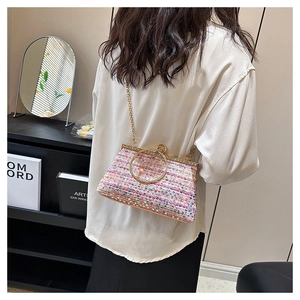 Detail of colorful tweed clutch with sequins, gold ring handle, and chain strap