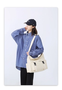 Détail du sac bandoulière en toile blanc cassé avec boucle noire et poche latérale