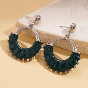 Detailed close-up of retro silver hoop earrings featuring dark green textured leather wrap