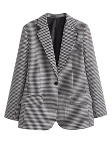 Detailed view of black and white houndstooth blazer with single button closure and flap pockets
