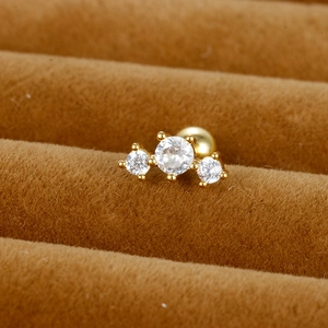 Vue macro de boucles d'oreilles à trois zircons ronds et fermoirs à boule dorés
