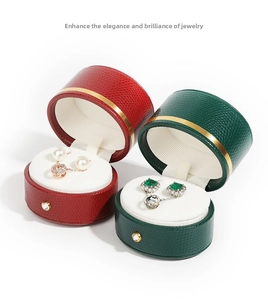 Close-up of circular PU leather jewelry boxes in red and green with soft flocking interior