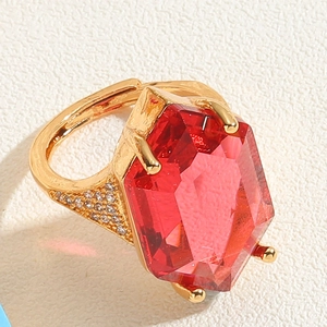 Macro detail of gold flower ring featuring a large red gemstone and zircon accents