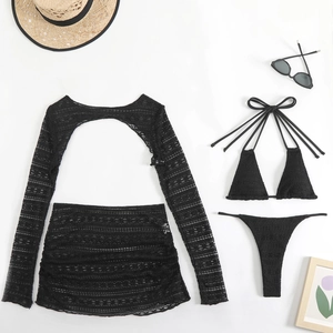 Flat lay of black crochet four-piece bikini set with sheer lace cover-up and beach skirt