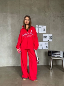 Detail of red athletic set with zip-up sweatshirt and wide-leg joggers in industrial setting