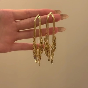 Detalle de pendientes largos de borla dorada con capas de hojas y diseño de caída elegante