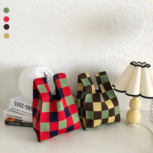 Detail of colorful checkered knit tote bags in red, green and coffee on a white desk