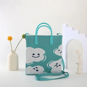 Mint green knitted tote bag with white cloud smiley face and adjustable shoulder strap