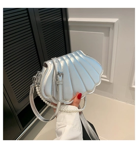 Detail of silver shell-shaped bag with pearl chain handle and quilted metallic finish