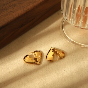 Polished 18K gold-plated stainless steel broken heart hoop earrings on a textured background