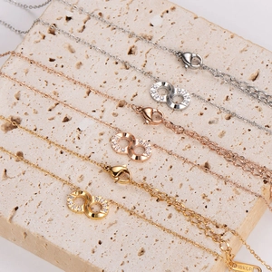 Three infinity loop pendant necklaces in gold, rose gold and silver finishes on stone
