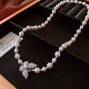 Détail macro d'un collier de perles avec pendentif papillon en zircon étincelant sur plateau