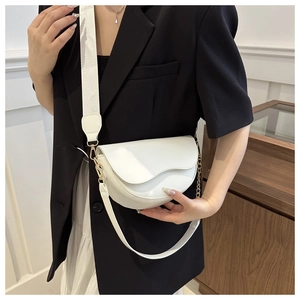 Détail du sac selle blanc en demi-lune avec bandoulière large et chaîne dorée décorative