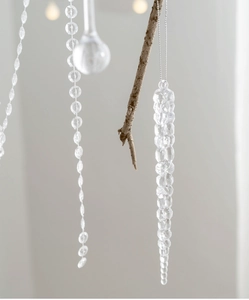 Macro shot of faceted crystal Christmas icicle pendant hanging on a natural branch