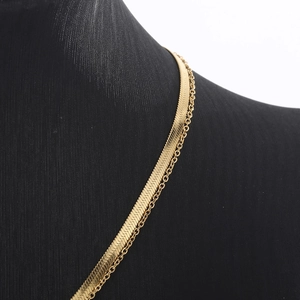 Close-up of golden double-layered herringbone and cable chain necklace on a model