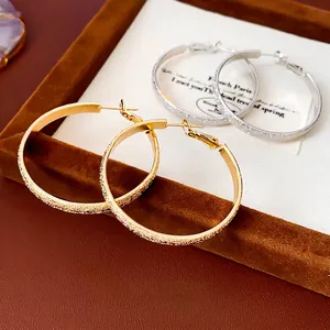 Polished silver and gold round hoop earrings with unique sandblasted textured surface