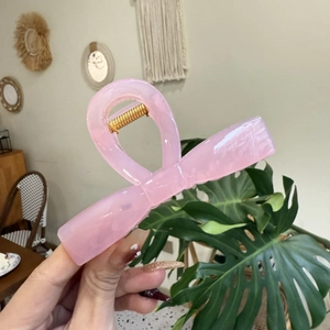 Nahaufnahme der rosa halbtransparenten Schleifen-Haarklammer mit goldener Metallfeder