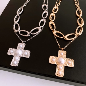 Detail view of double-layer chain necklaces with gold and silver pearl cross pendants