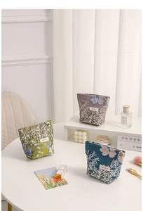 Detailed view of three floral jacquard cosmetic pouches organized on a white vanity table