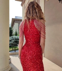 Detailed view of red sequin evening gown with delicate beaded tassels on shoulders